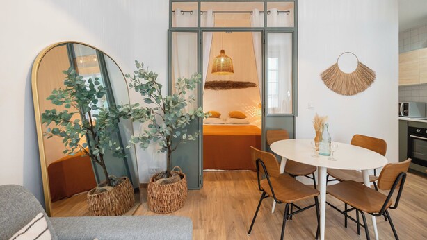 A modern living room with a round dining table, chairs, a large mirror, and a potted plant. - T2 Tout Confort - Central- Bord de mer 100m - Clim (La Ciotat)