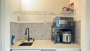 A compact kitchen with a sink, a microwave, a coffee maker, and a shelf above the counter. - Your Private Space - Nothing Shared (Brampton)