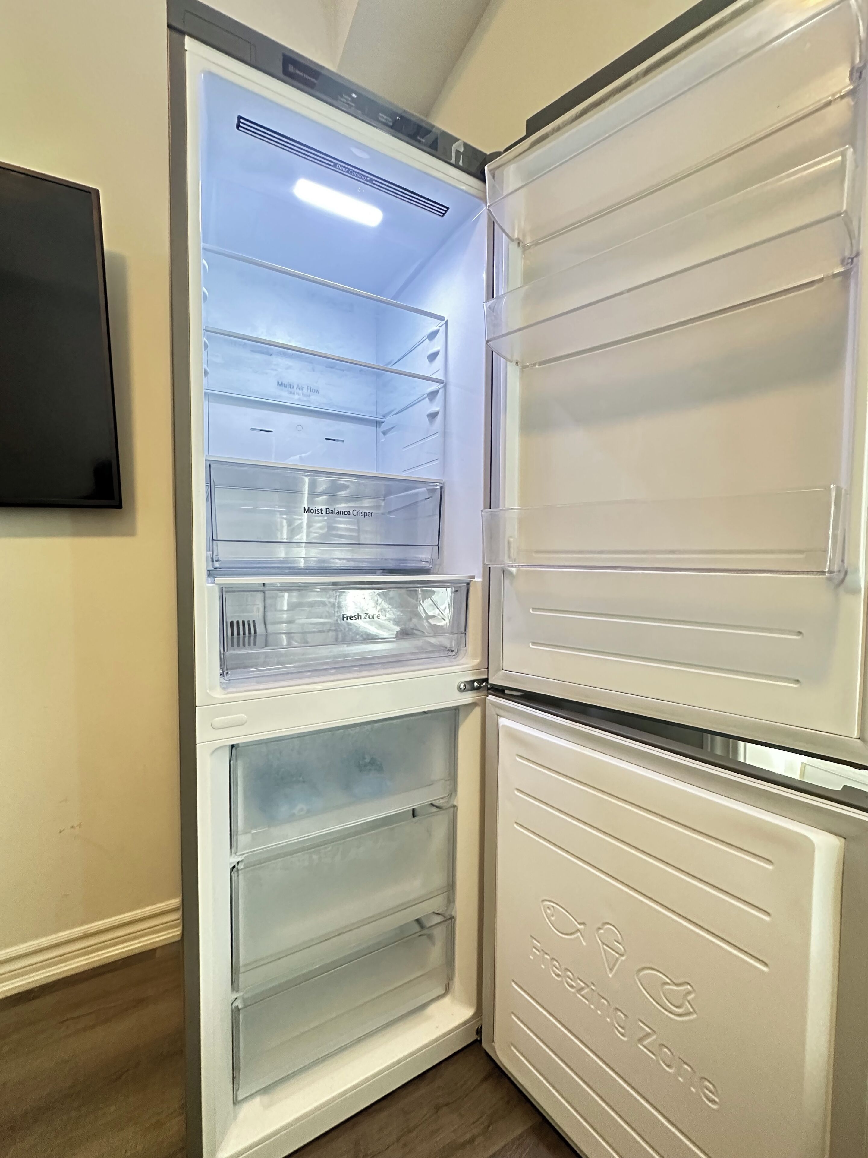 A white refrigerator with multiple compartments, including a 'Moist Balance Crisper' and a 'Fresh Zone.'