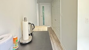 A narrow hallway with a dark floor, white walls, and a door at the end. - Your Private Space - Nothing Shared (Brampton)