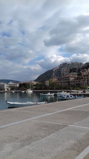 A marina with boats docked, a pebble beach, and buildings in the background. - Margarita's Cottage
 Ήσυχο και Άνετο σπίτι, 5 λεπτά απο το ιστορικό Ναύπλιον. (ΝΑΥΠΛΙΟΝ)