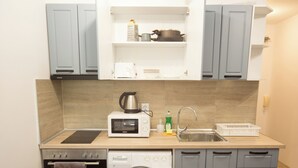 Cocina compacta con microondas, tetera, lavabo y lavadora.