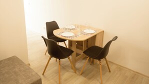 Un comedor con una mesa redonda, cuatro sillas negras y un banco.