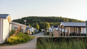 A row of mobile homes with a pathway leading to a hill. - Luxuriöses Chalet in Fußnähe zum Strand (Biggekerke)