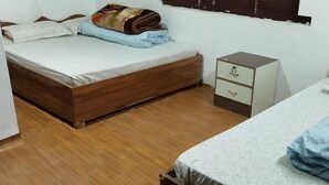 A bedroom with a wooden bed, a bedside table with drawers, and a small nightstand. - Hotel D4 Red Mud (Thuli Bheri)
