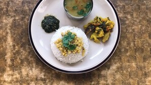 A plate with white rice topped with yellow lentils and a green garnish, a bowl of soup, and a side of mixed vegetables. - Hotel D4 Red Mud (Thuli Bheri)