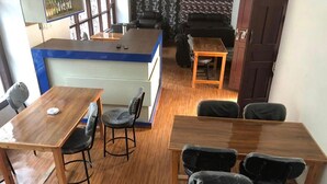 A room with a wooden floor, a reception desk, and several tables and chairs. - Hotel D4 Red Mud (Thuli Bheri)