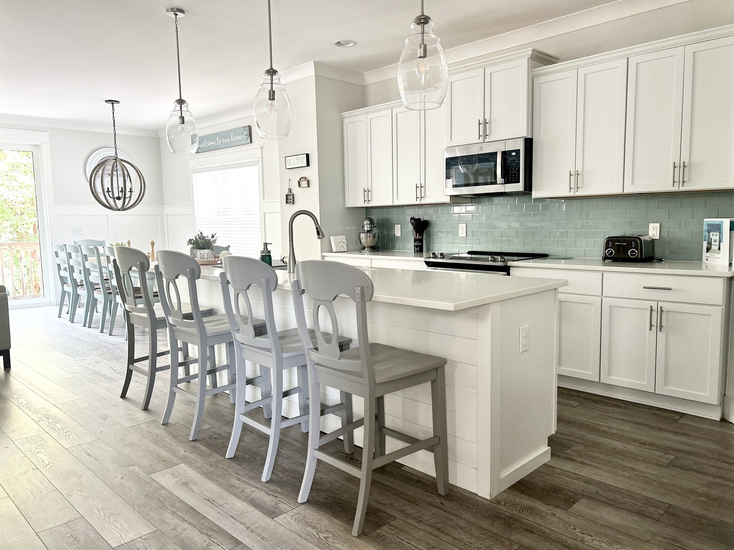 Una cocina moderna con armarios blancos, una isla central e iluminación colgante.