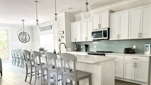 A modern kitchen with white cabinets, a central island, and pendant lighting. - Luxury 6-Bedroom Home with Private Pool, Elevator & Family-Friendly Comfort (Hilton Head)