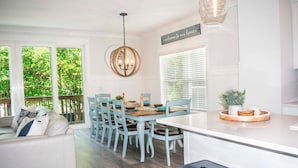 A bright, spacious kitchen with a dining area, featuring a white and blue color scheme, a chandelier, and a welcoming sign. - Luxury 6-Bedroom Home with Private Pool, Elevator & Family-Friendly Comfort (Hilton Head)