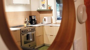 Una cocina con techo de madera, estufa, cafetera y ventana.