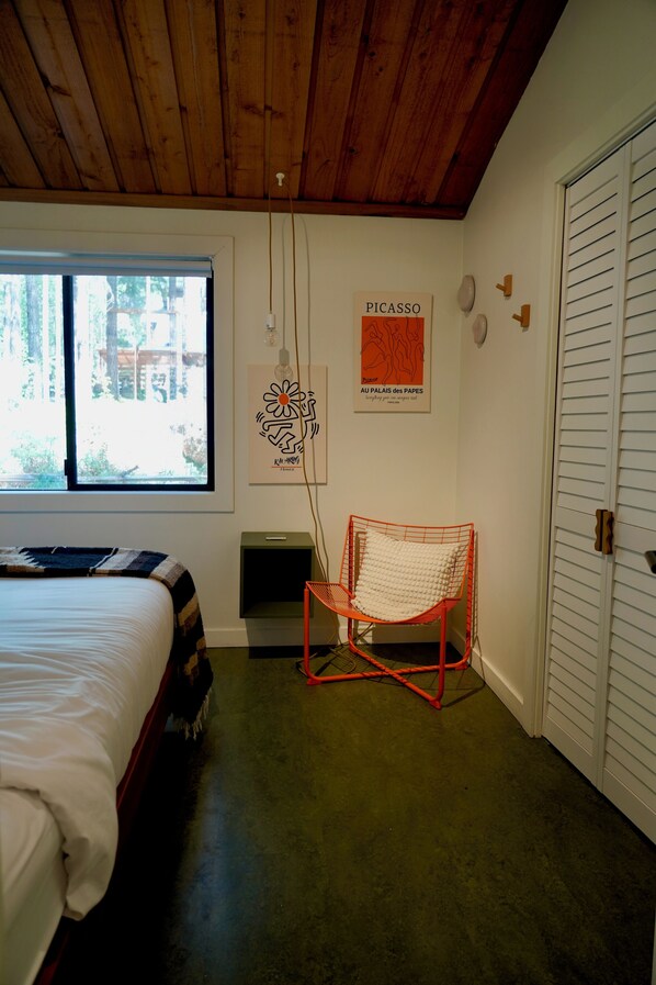 Un dormitorio con cama, ventana, silla y puerta.