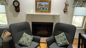 A living room with two grey armchairs, a fireplace, and a painting above it. - Relax or be active! The choice is yours in this pet-friendly family home.  (Norfolk)