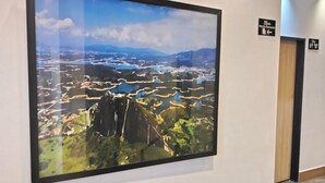 Un pasillo con una fotografía grande enmarco de un paisaje, un letrero que indica un baño y una puerta con la leyenda "Piso 2".