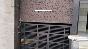 Una verja metálica cerrada con un muro de metal perforado encima.