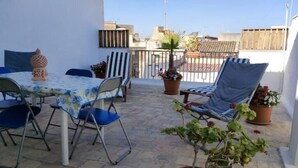Un pati amb taula i cadires, plantes en testos i vista de la ciutat.