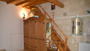 Una escalera de madera con una silla al pie, un armario de madera y un espejo sujeto a la pared.