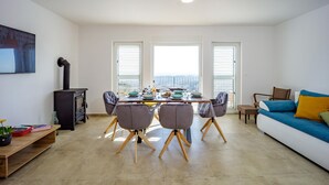 Una sala de estar moderna con comedor, sofá, televisor y chimenea.