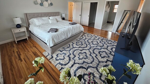 A bedroom with a bed, nightstand, wall decor, ceiling fan, and a large mirror. - Spacious 1 story Home in Rapid City Historic District (Rapid City)