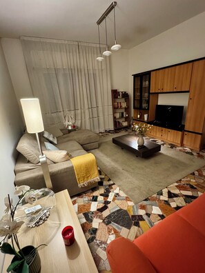 Una sala de estar moderna con un sofá modular, una mesa de centro, un televisor y una estantería.