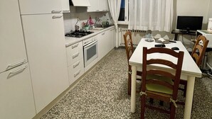 Eine kleine Küche mit weißen Schränken, einem Herd und einem Esstisch mit Stühlen.