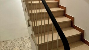 Eine Treppe mit einer Holztür am oberen Ende, weißen Wänden und einem schwarzen Geländer.