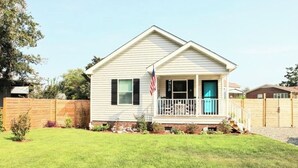 Ein eingeschossiges Haus mit Veranda, kleiner Terrasse und einer amerikanischen Flagge.