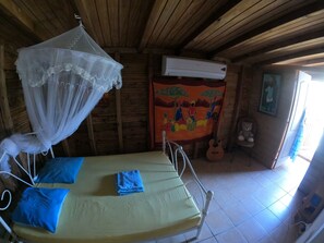 Ein Patientenzimmer mit Bett, Moskitonetz, Klimaanlage, einem Bild und einem Teddybären.