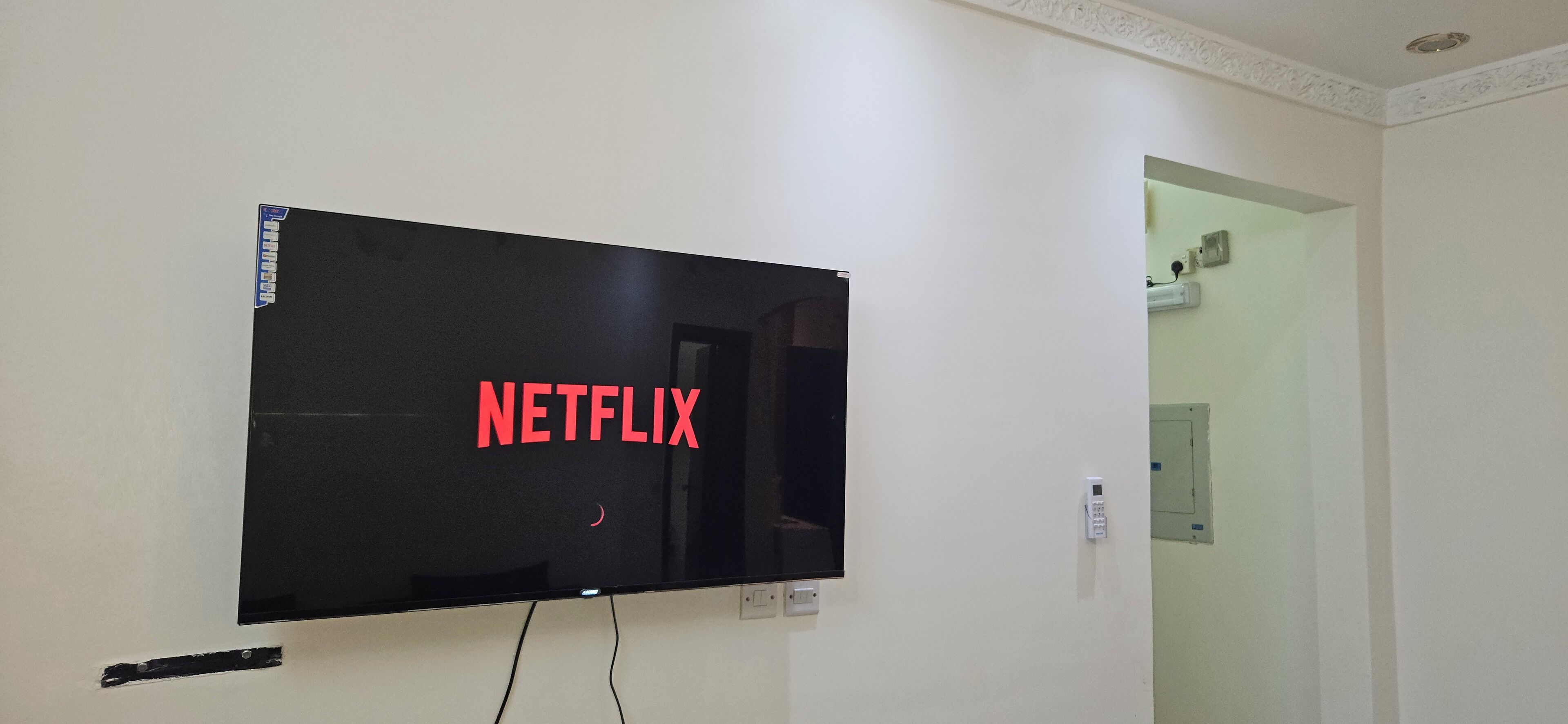 A television mounted on a wall with the word "NETFLIX" displayed on the screen.