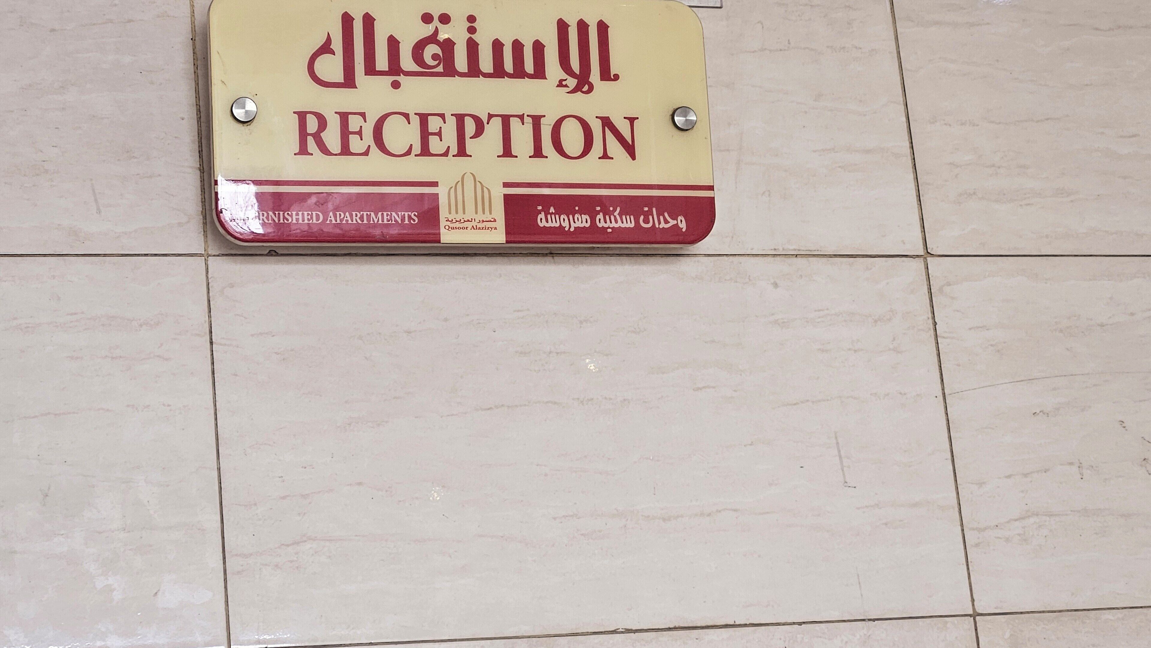 Segnaletica della reception per appartamenti ammobiliati con testo arabo e traduzione in inglese.