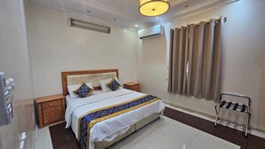 Une chambre bien rangée, avec un lit, des tables de chevet, une commode, une chaise et une fenêtre avec des rideaux.