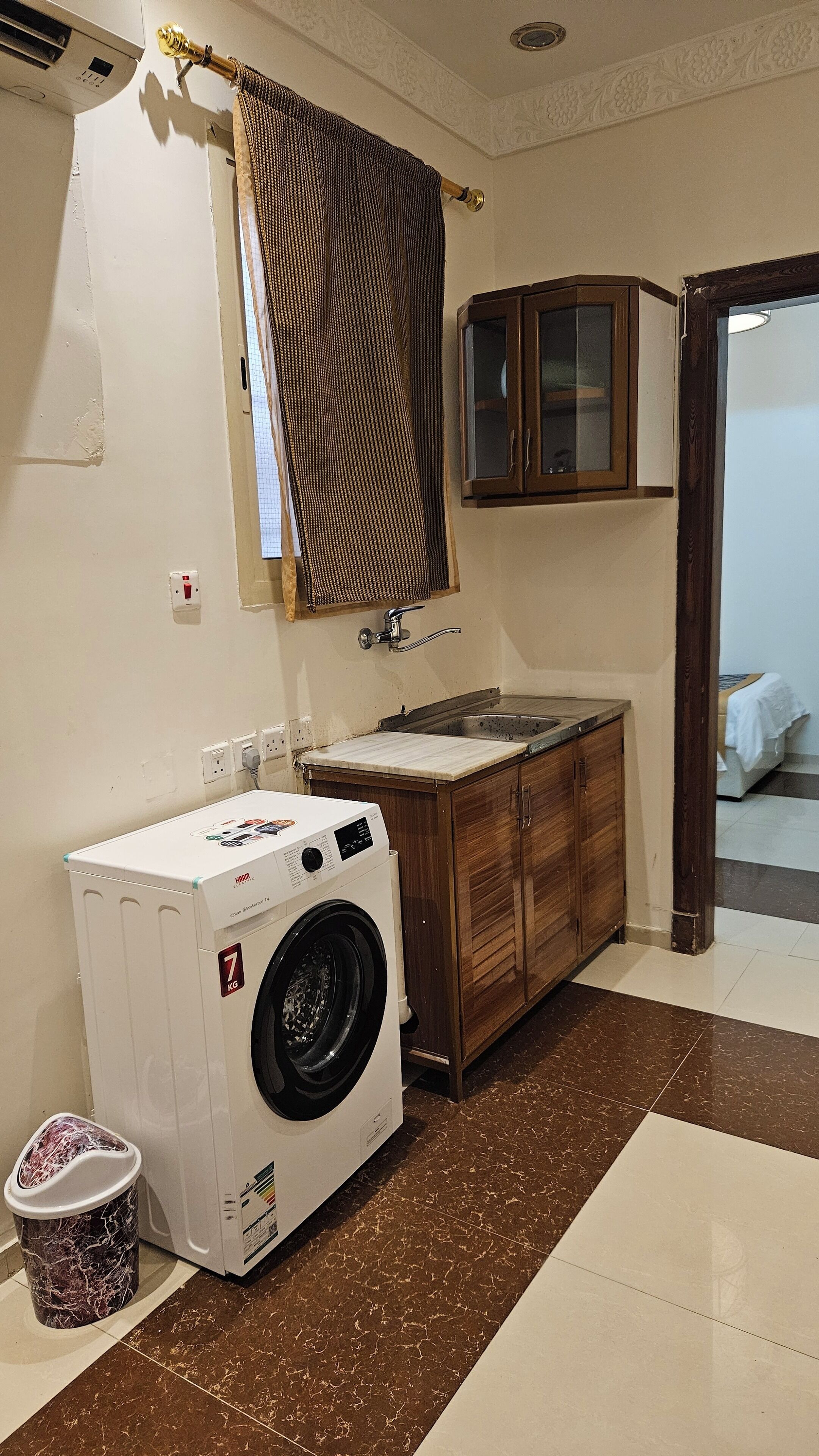 A compact kitchen with a washing machine, a sink, and wooden cabinets.
