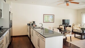 A modern kitchen with a central island, a dining area with a table and chairs, a television, and a ceiling fan.