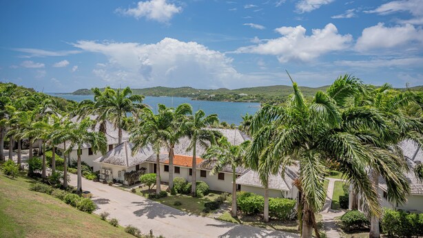 A coastal resort with multiple bungalow-style buildings, palm trees, and a view of the sea.