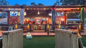 A building with a thatched roof, colorful murals, and a covered outdoor seating area. - Lake Front Cabin! 
Pool, Basketball, Boat parking & Firepit. Lots of parking. (Brookeland)