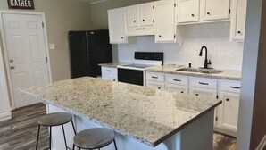 A kitchen with white cabinets, a granite countertop, a black refrigerator, and a sink. - Lake Front Cabin! 
Pool, Basketball, Boat parking & Firepit. Lots of parking. (Brookeland)