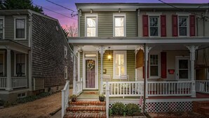 A two-story house with a porch, a front door with a wreath, and a small garden area. - Historic Annapolis Home! (Annapolis)