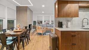 Eine moderne Küche mit Holzausstattung, eine Essecke mit Tisch und Stühlen sowie eine gemütliche Sitzecke mit Sofa und Kaffeemaschine.