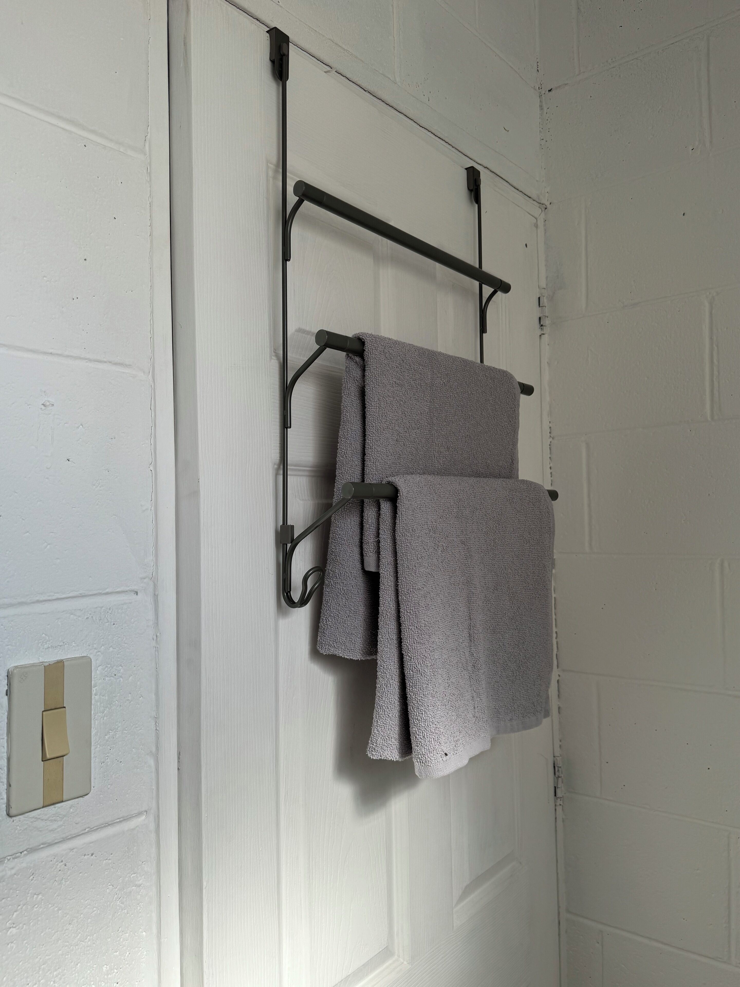 Une porte blanche avec un porte-serviettes sur lequel sont accrochées deux serviettes.