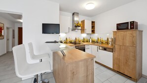A modern kitchen with a glass dining table, white chairs, wooden cabinets, a built-in oven, and a microwave. - 2 bedroom nice home in Rotthalmünster (Rotthalmünster)