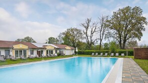 A swimming pool with lounge chairs and a building with a tiled roof. - 2 bedroom nice home in Rotthalmünster (Rotthalmünster)