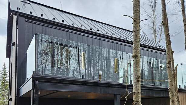 A modern two-story building with a glass facade, a wooden deck, and a hot tub.