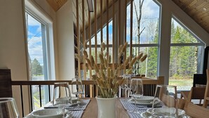 A dining table set with plates, glasses, and cutlery, with a vase of pampas grass in the center.