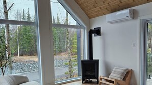 A modern living room with large windows, a fireplace, and a cozy seating area.