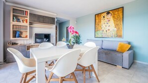 Ein modernes Wohnzimmer mit Essbereich, einer Couch und einem Gemälde an der Wand.