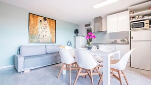 Eine moderne Küche mit weißen Schränken, einem Esstisch mit Stühlen und einem großen Gemälde an der Wand.