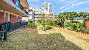 Ein Wohngebiet mit einem grünen Innenhof, einem umzäunten Garten und mehrstöckigen Gebäuden mit Balkonen.