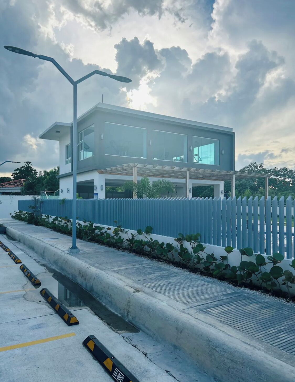 Un edificio moderno con ventanas amplias, techo plano y valla blanca.