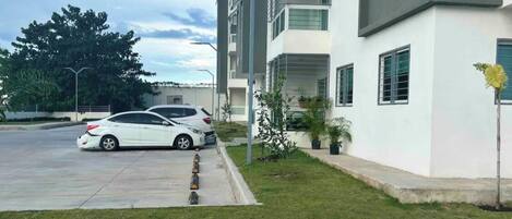 Un edificio residencial moderno de varios pisos con un estacionamiento al frente.