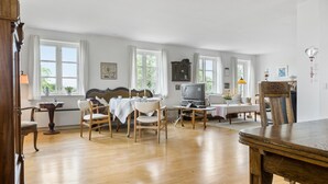 A spacious room with wooden flooring, a dining table with chairs, a television, and a cabinet. - Nice home in Sønderborg with kitchen (Sønderborg)